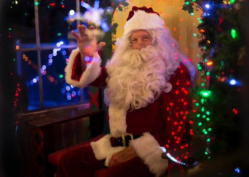 santa claus sitting on a chair and waving to the camera